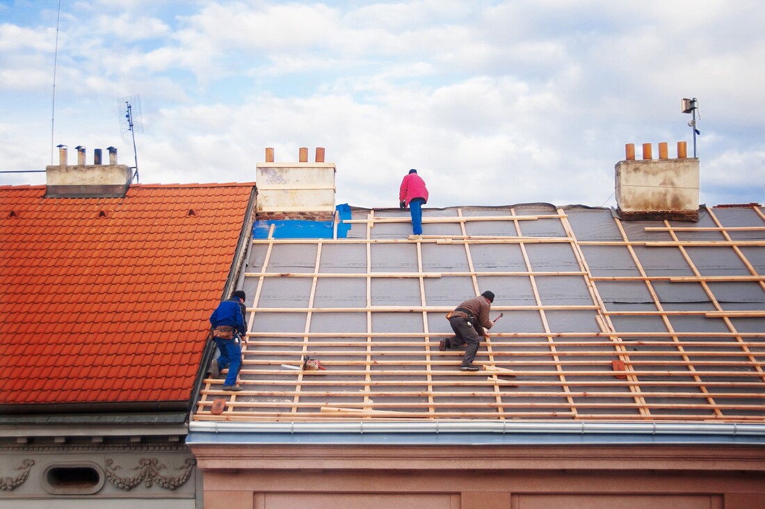 An image of three persons working on a roof replacement service