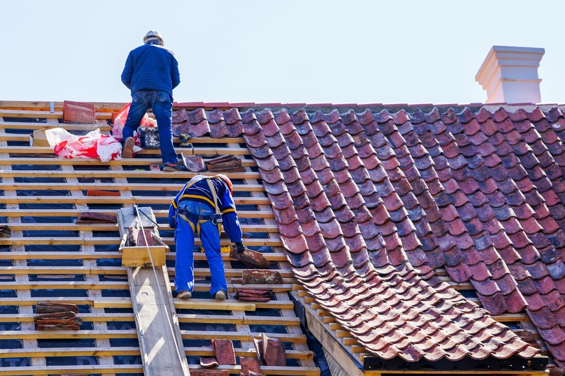 An image of two persons working on a roof replacement service